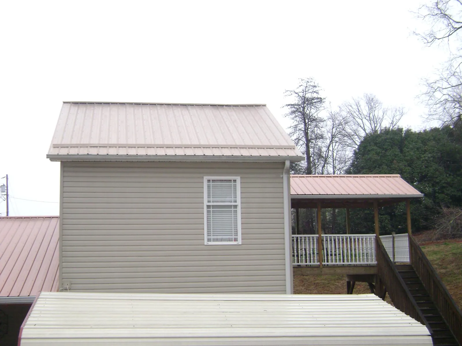 Tan metal roofs on a two story addition and attached porch, from a Roof Replacement job in Sierra Vista