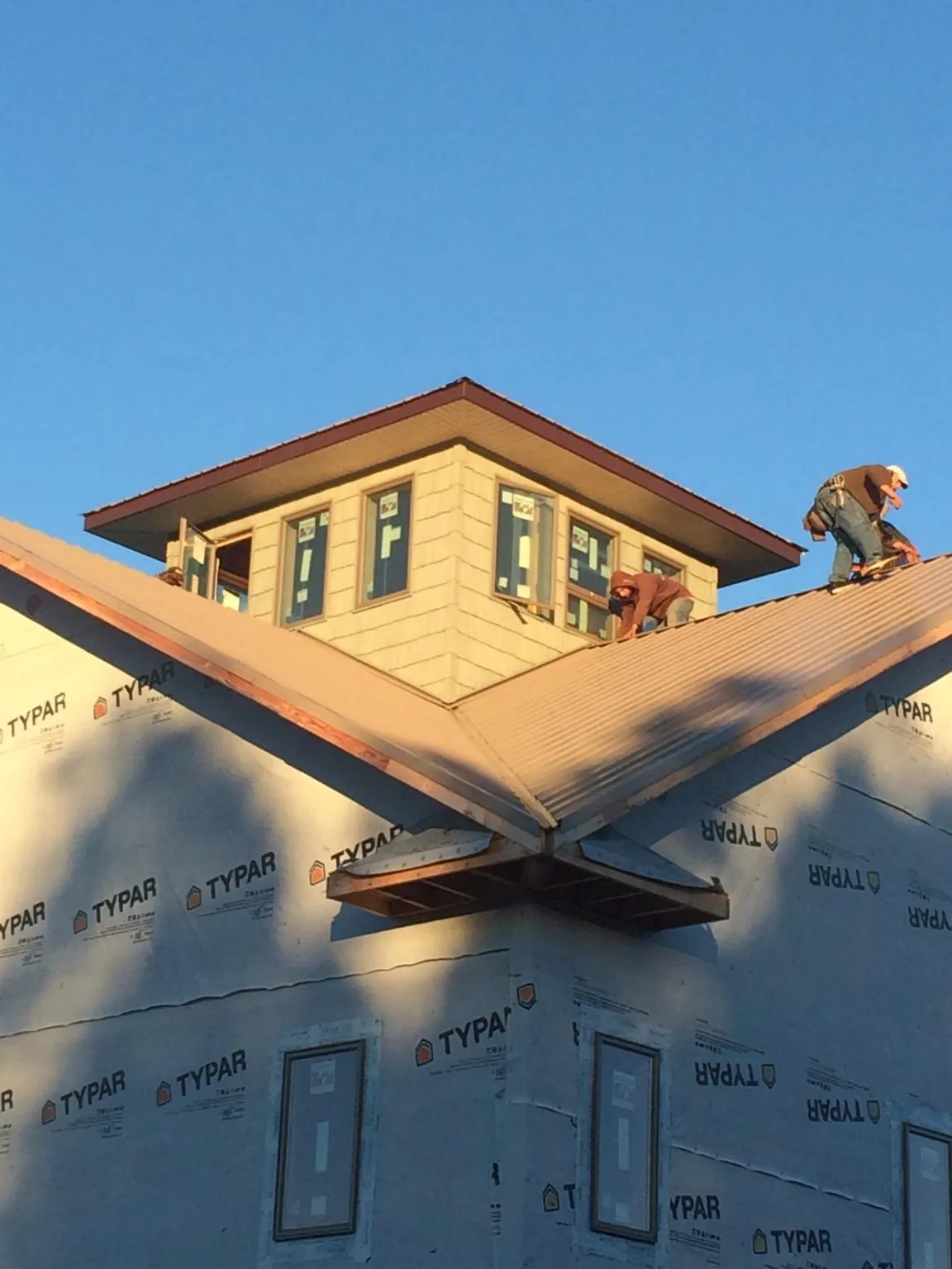 Roofers working around a rooftop cupola on a new metal roof at sunset — Roof Waterproofing in Sierra Vista by Roofing Brothers